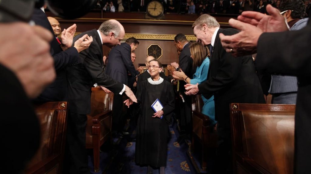 Ruth Bader Ginsburg shaking hands with other people inside a courtroom